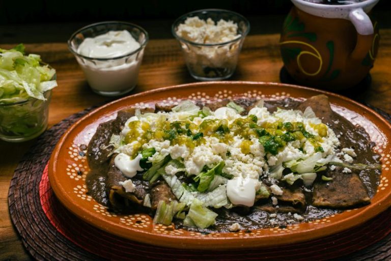 Authentic enfrijoladas served at La Neta with creamy pinto bean sauce, queso, sour cream, and fresh toppings, a classic Mexican comfort dish found locally.
